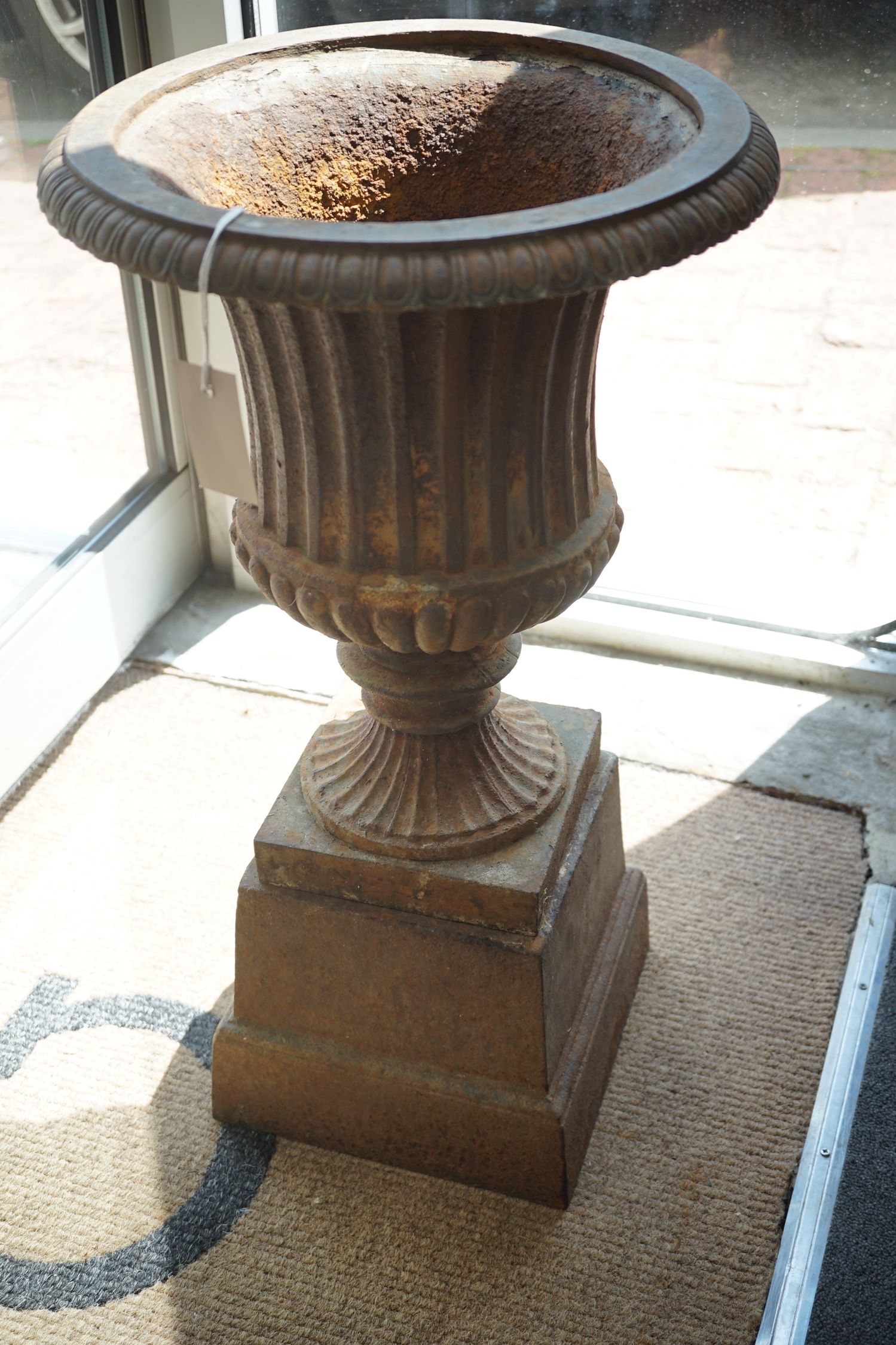 A Victorian style cast iron campana garden urn on a square plinth, diameter 38cm, height 68cm
